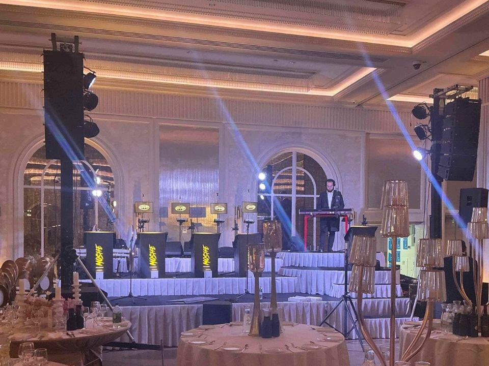 Ballroom with flown line array speakers on both sides of the stage and a live band